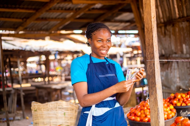 Mulher do mercado segurando a moeda da Nigéria