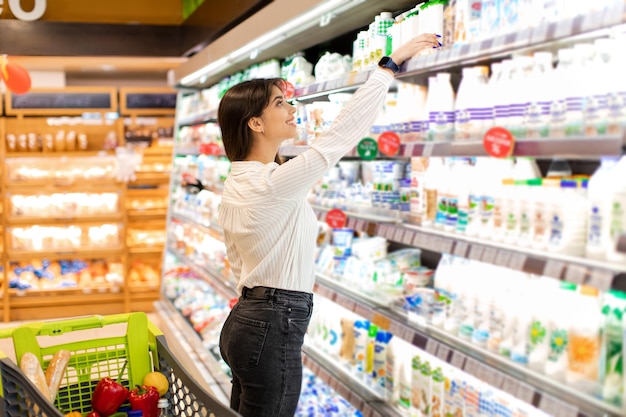 Mulher do Oriente Médio fazendo compras de produtos lácteos no supermercado