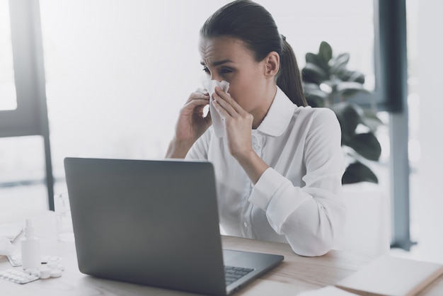 Mulher doente sentado no seu local de trabalho no escritório.