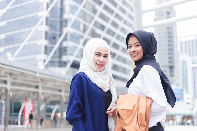 Mulher dois muçulmana asiática que está e que sorri olhando a câmera na cidade.