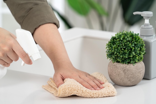 Mulher dona de casa está fazendo a limpeza de primavera na cozinha de casa com o uso de limpador de garrafa de pulverização de pano para limpar a superfície da mesa do balcão