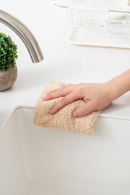 Foto mulher dona de casa está fazendo a limpeza de primavera na cozinha de casa com o uso de pano, pulverizando limpador de garrafa para limpar a superfície da mesa do balcão.