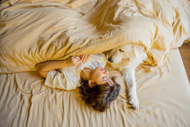 Mulher dorme com seu cachorro fofo na cama