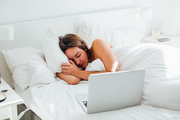 Mulher dormindo com laptop na cama em casa