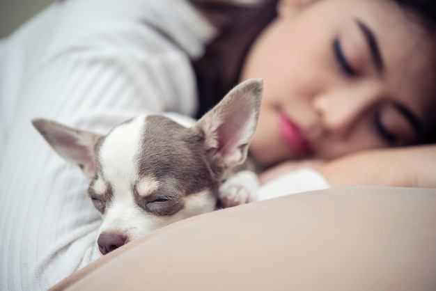 Mulher dormindo com seu cachorro fofo na cama.