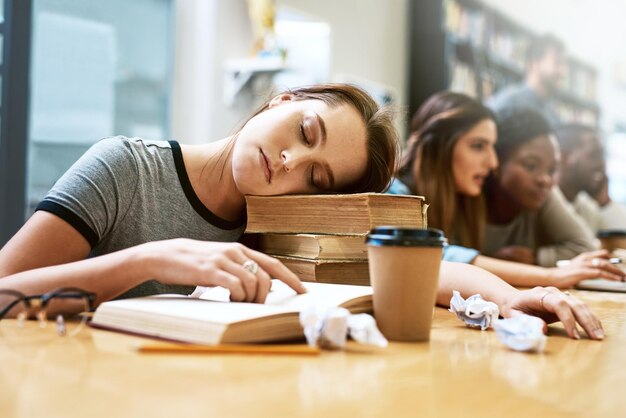 Mulher dormindo e livros para estudar na faculdade de biblioteca e cansada com estresse, ansiedade ou esgotamento Estudante universitária e dorme com estudo educacional e fadiga com notas escolares e mesa
