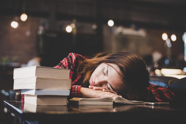Mulher dormindo em um livro em uma mesa em um café