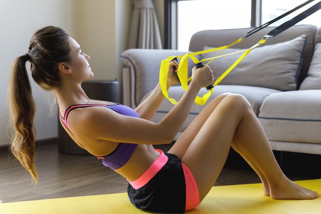 Foto mulher durante o treino em casa com correias de suspensão