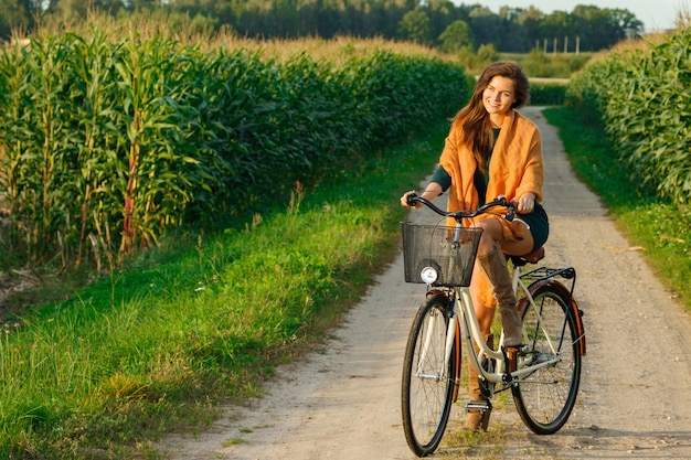 Mulher é andar de bicicleta pela estrada rural no milharal