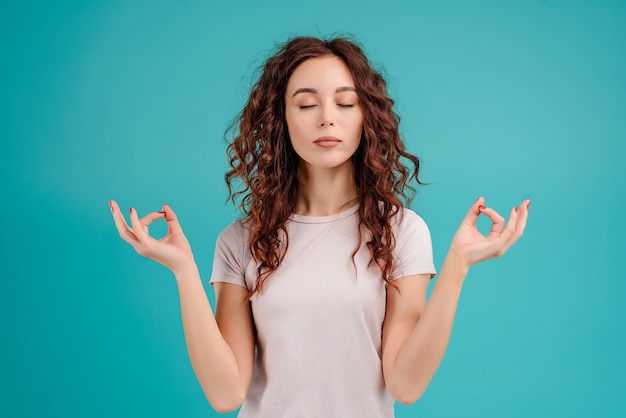 Mulher é calma e relaxada com gestos zen isolados sobre fundo azul turquesa