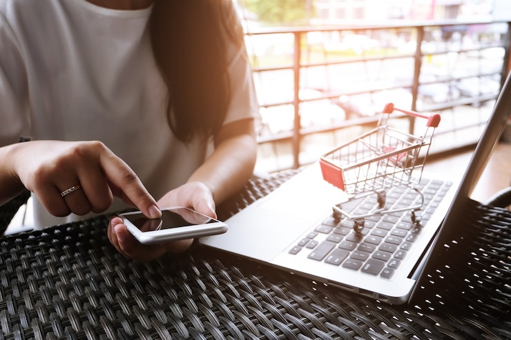 Foto mulher e carrinho de compras pequeno com laptop para o conceito de compras online na internet.
