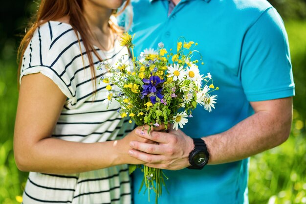 Mulher e homem de mãos dadas menina com buquê de conceito de amor de camomilacasal apaixonadodatacasal amoroso está segurando o buquê de flores silvestres