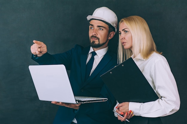 Mulher e homem em um capacete de construção com um laptop