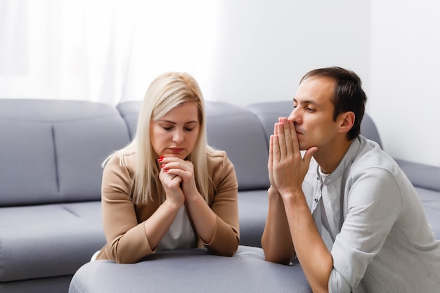 Mulher e homem rezam em casa