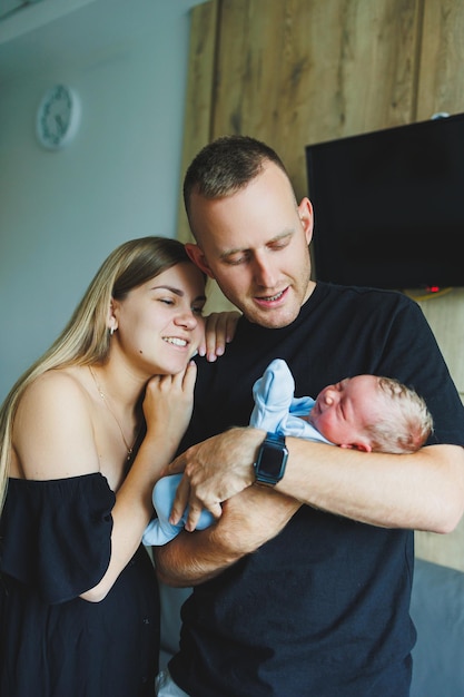 Foto mulher e homem segurando um recém-nascido mãe, pai e bebê closeup retrato de uma jovem família sorridente com um recén-nascido nas mãos família feliz em fundo