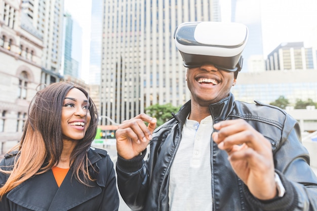 Mulher e homem sorrindo enquanto ele tenta fone de realidade virtual