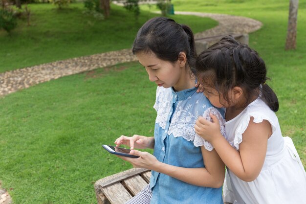 mulher e menina com telefone móvel no parque natural