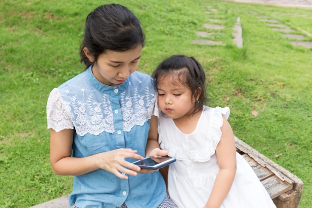 mulher e menina com telefone móvel no parque natural