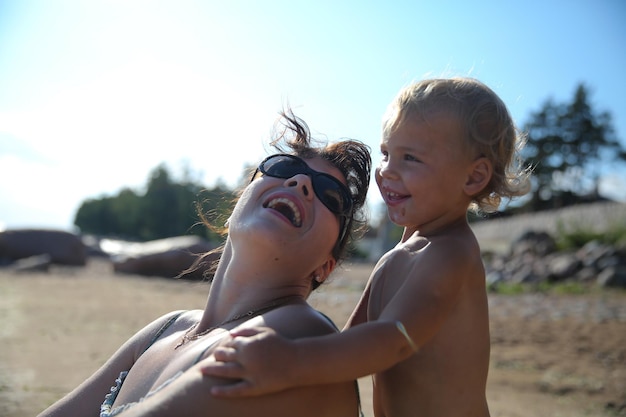 Mulher e menino felizes na praia contra o céu