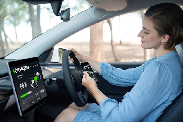 Foto mulher eco-consciente no assento do condutor a verificar a bateria dos carros elétricos perpétua