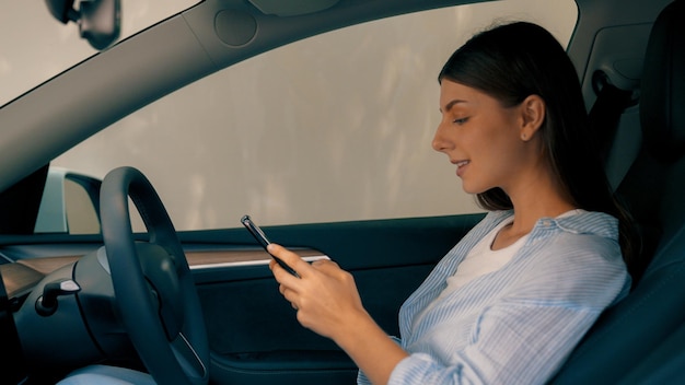 Mulher ecoconsciente no assento do motorista segurando um telefone Exalt com tela de copyspace em branco