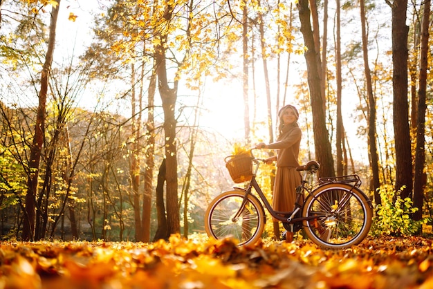Mulher elegante com bicicleta aproveitando o clima de outono no parque Mulher bonita na floresta de outono
