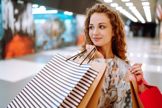 Mulher elegante com bolsas multicoloridas no centro da loja A alegria do consumo