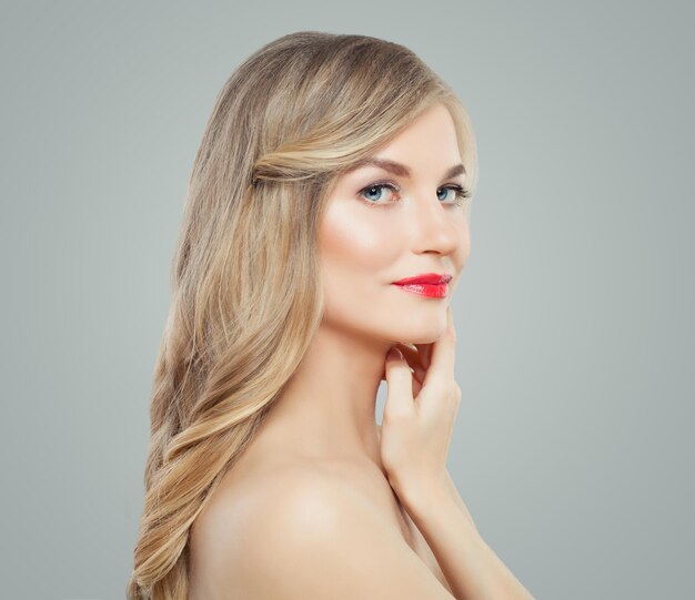 Mulher elegante com cabelos loiros longos e encaracolados, pele saudável e maquiagem de lábios vermelhos, tratamento facial, cuidados com os cabelos e conceito de cosmetologia