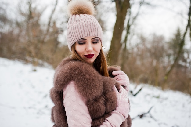 Mulher elegante com casaco de pele e chapelaria na floresta de inverno.