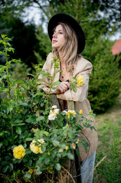 Mulher elegante com chapéu e jaqueta em um antigo jardim rural