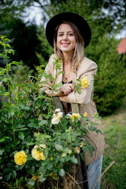 Mulher elegante com chapéu e jaqueta em um antigo jardim rural