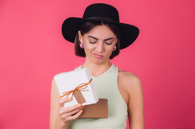 Mulher elegante com chapéu na parede rosa vermelha