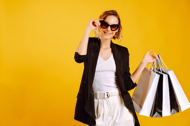 Mulher elegante com óculos escuros segurando sacolas de compras