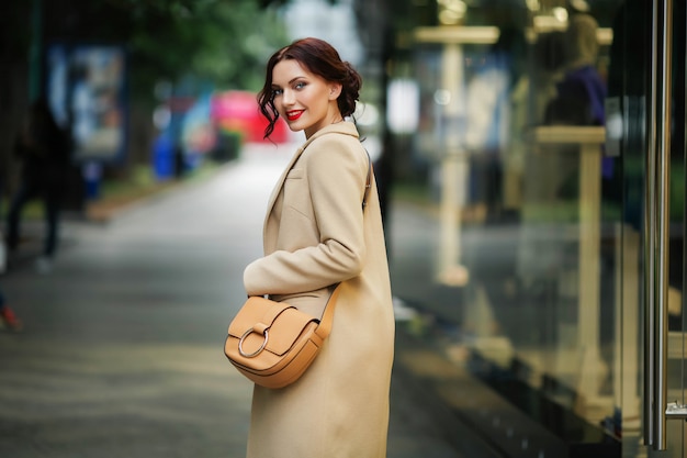 Mulher elegante com um casaco branco em uma rua com lojas