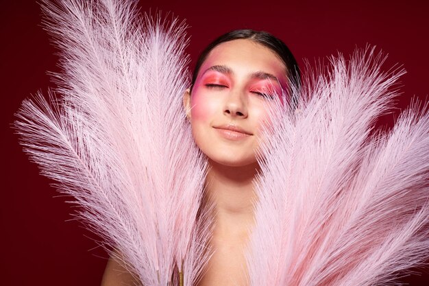 Mulher elegante com uma maquiagem brilhante pente posando penas fofas fundo rosa inalterado