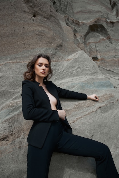 Foto mulher elegante de terno posando em pedras de areia