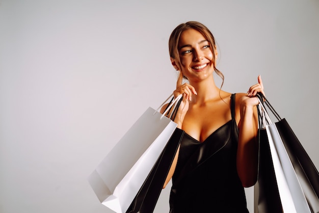 Mulher elegante de vestido preto segurando sacolas de compras