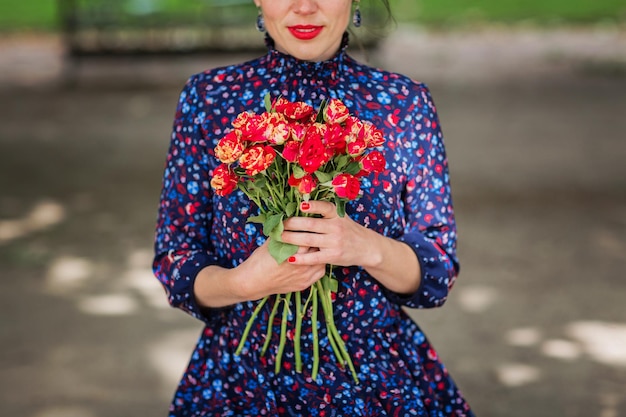 Mulher elegante e irreconhecível segurando um buquê de rosas vermelhas