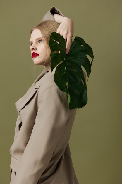 Mulher elegante em casaco lábios vermelhos moda folha de palmeira fundo verde