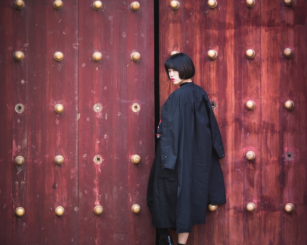 mulher elegante em pé na frente da porta de madeira tradicional