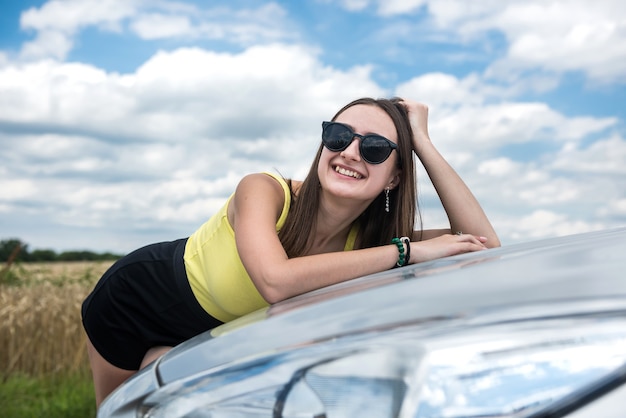 Mulher elegante em pé perto de seu carro e desfrutar da liberdade na natureza fora da cidade