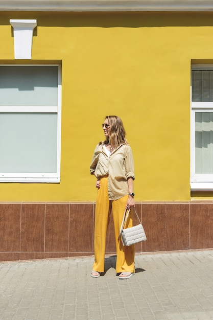 Mulher elegante em roupa amarela contra uma parede de cor brilhante
