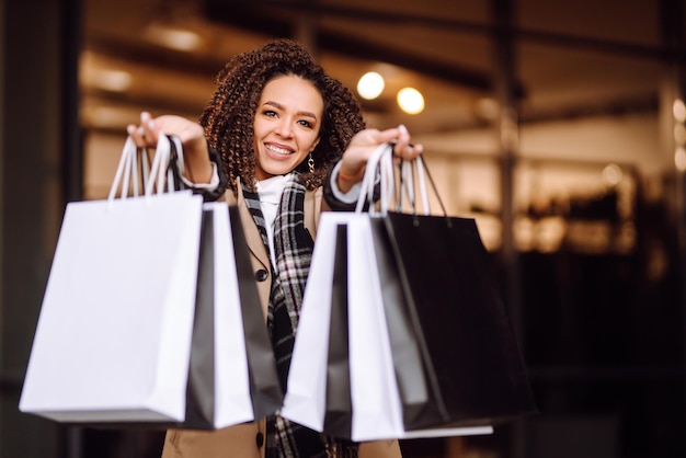 Foto mulher elegante em roupas da moda com sacolas de compras perto do shopping mulher depois das compras