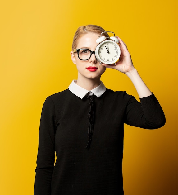 Mulher elegante em roupas formais pretas com despertador