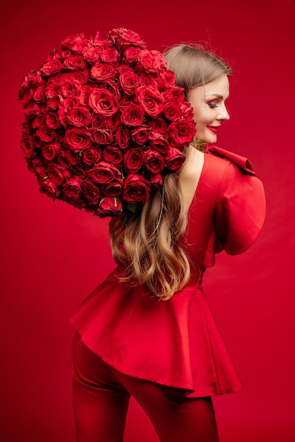 Mulher elegante em roupas vermelhas segurando flores