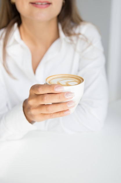 Mulher elegante está segurando uma xícara de café cappuccino