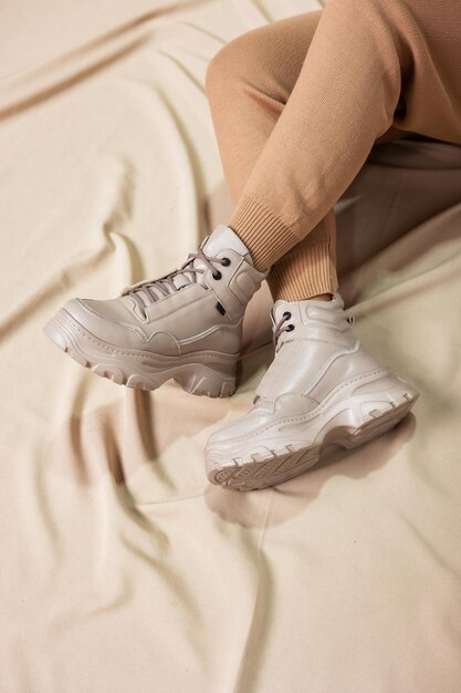 Mulher elegante fica em sapatos bege. Close-up de pernas femininas em botas vintage de couro na moda bege. Nova coleção sazonal de calçados femininos