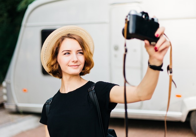 Mulher elegante hippie com chapéu faz selfie retrato usando câmera retro.