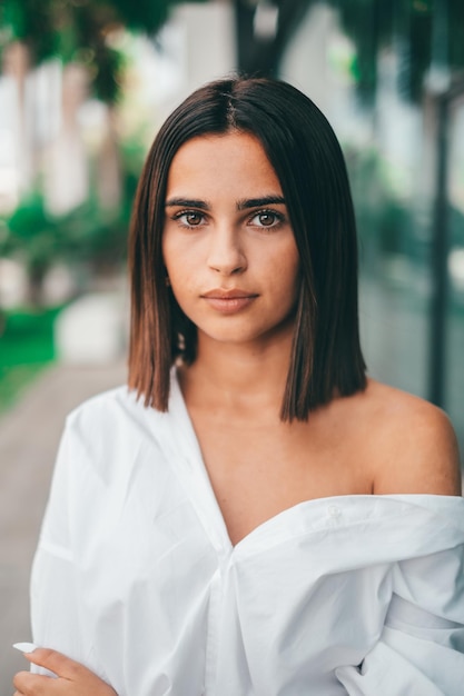 Foto mulher elegante jovem feliz com cabelo curto, olhando para a câmera ao ar livre. linda senhora satisfeita com cabelo curto, sorrindo enquanto olha para a câmera. retrato de jovem confiante sorrindo