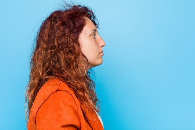 Foto mulher elegante jovem ruiva olhando para a esquerda, pose de lado.